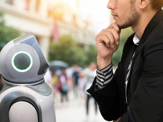 A main interacting with a robot in the street.