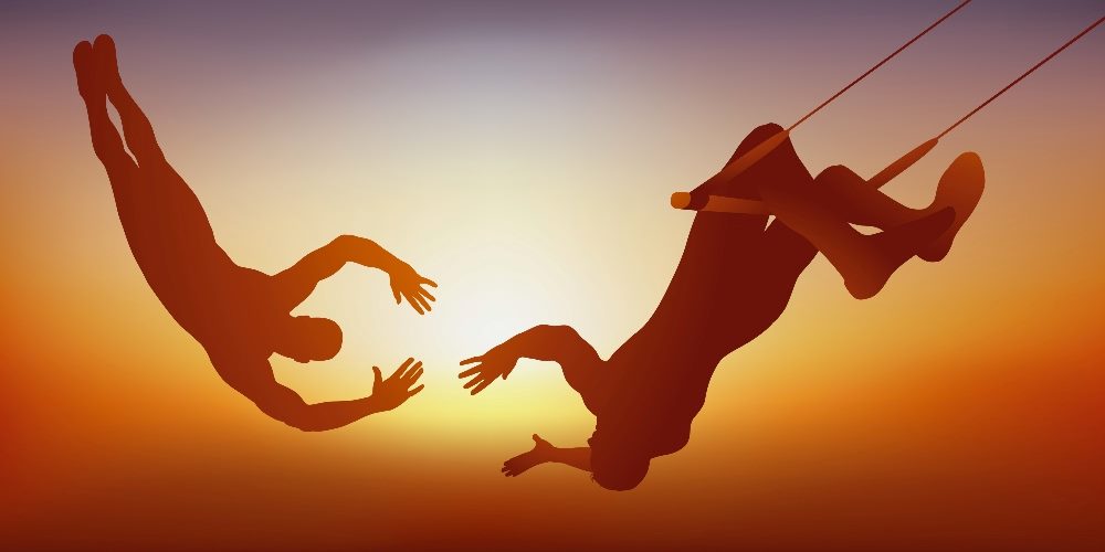 Two trapeze artists swing toward each other in an aerobatics act against a gorgeous sunset in piece about customer trust.