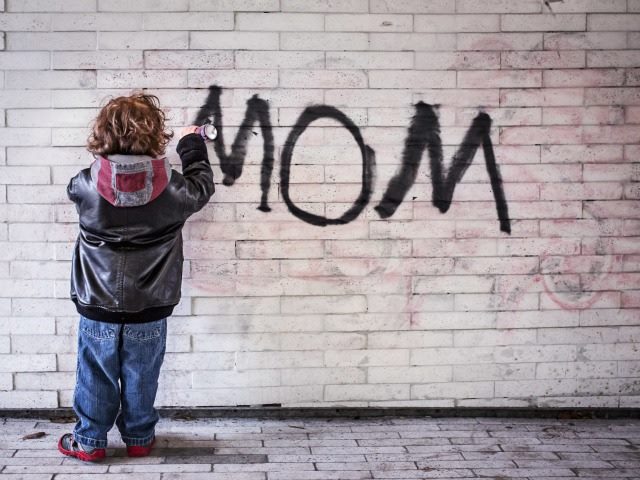 boy writing 'mom' on a wall
