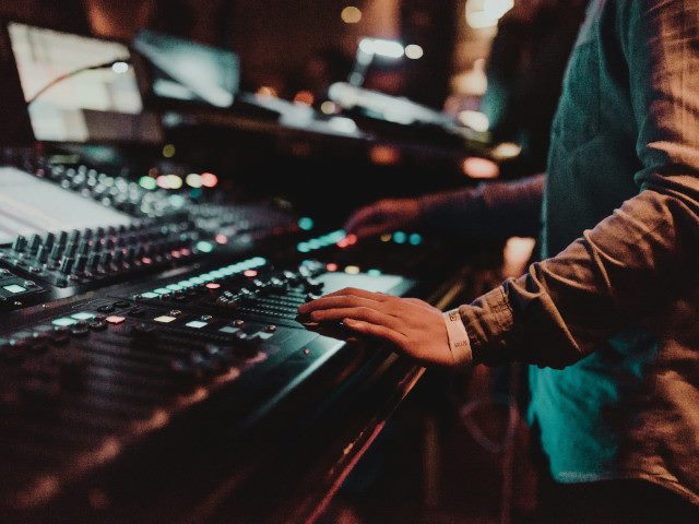 An audio engineer works a sound board during a live music event.