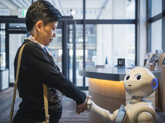 Robot welcoming businesswoman into the office