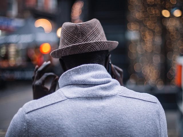 man walking down the street, talking on his phone, giving the OK sign