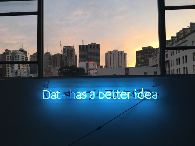 A neon sign below a window that reads data has a better idea. The sign is lit. The window looks out over a city. - Customer data concept