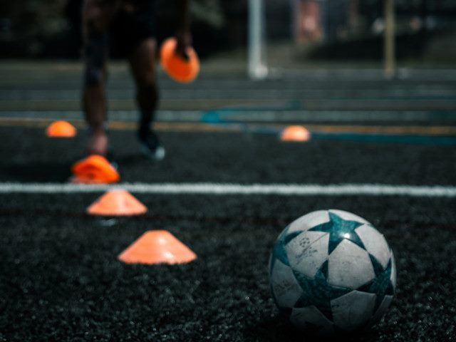 A soccer ball and practice drill cones on a field.