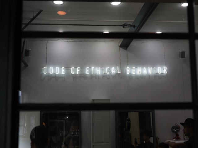 A storefront with a neon sign above it that says code of ethical behavior - AI ethics concept