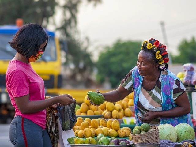 A woman selling fruit to another woman.