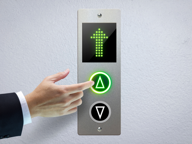 the hand of a man pressing the elevator button for next level up
