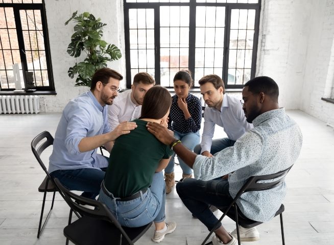 Group of people sitting down in a circle being compassionate for one of the individuals.