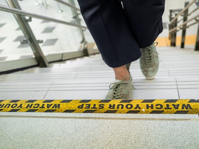 close up of a person walking up steps with caution tape on the top