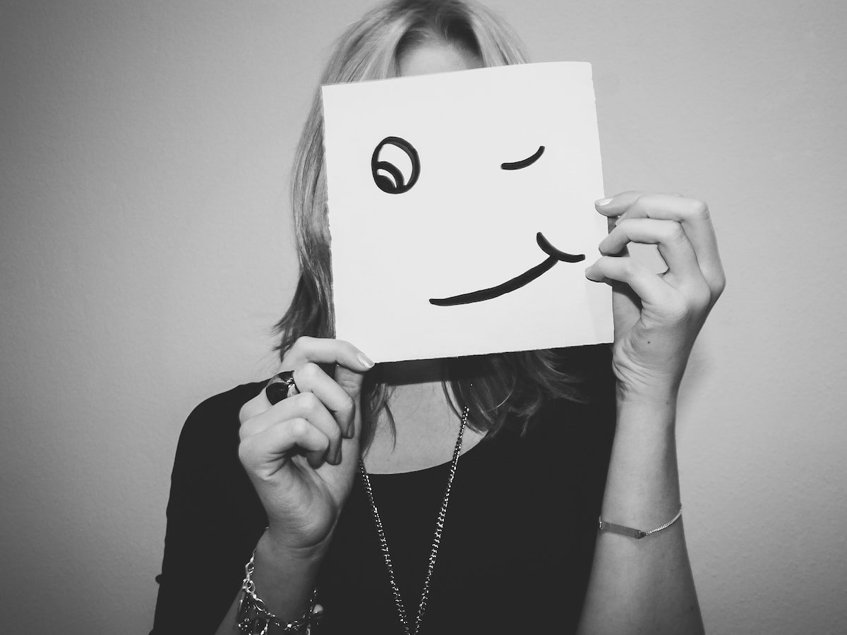 woman hiding her face behind a drawing of a face