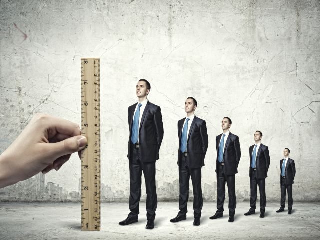 Employers hand measuring potential skills of employees standing in line with a ruler