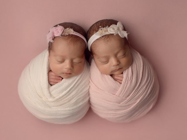 Two newborn babies sleeping wrapped in a blanket