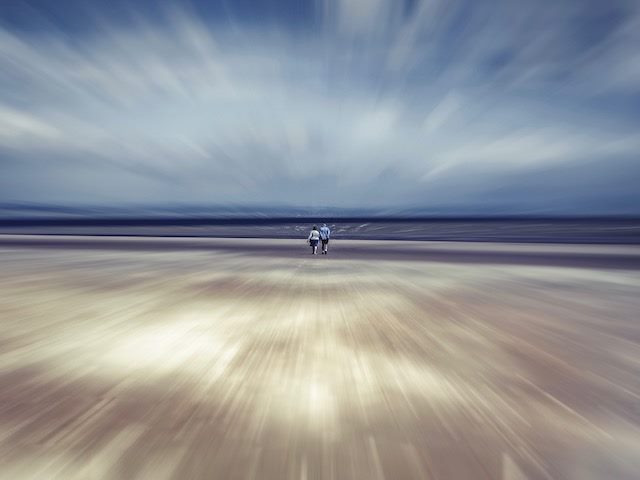 focus on  couple walking towards horizon with motion around them