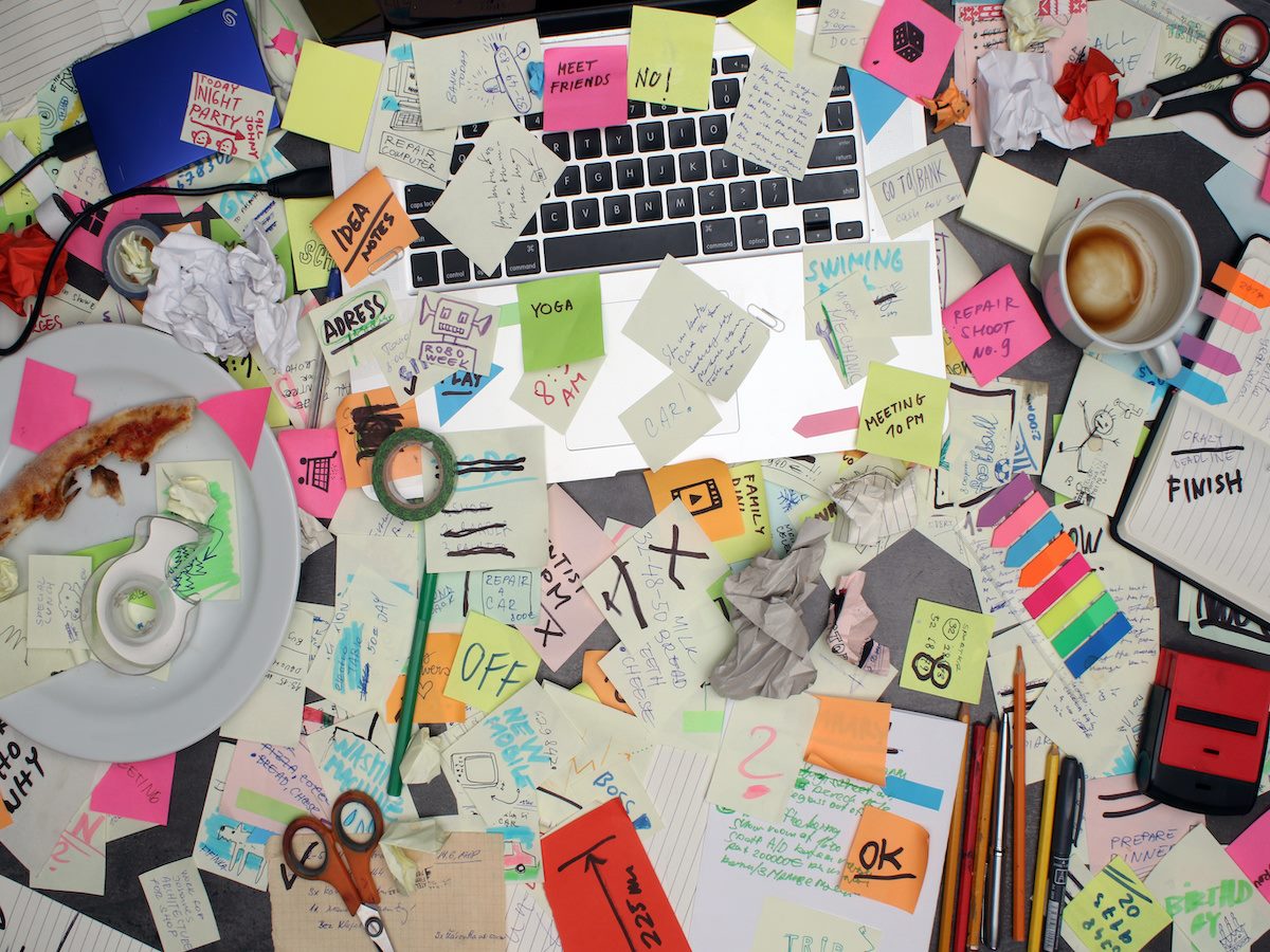 office desk with laptop computer and post it notes all around