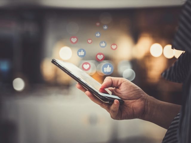 Woman holding phone with likes and shares