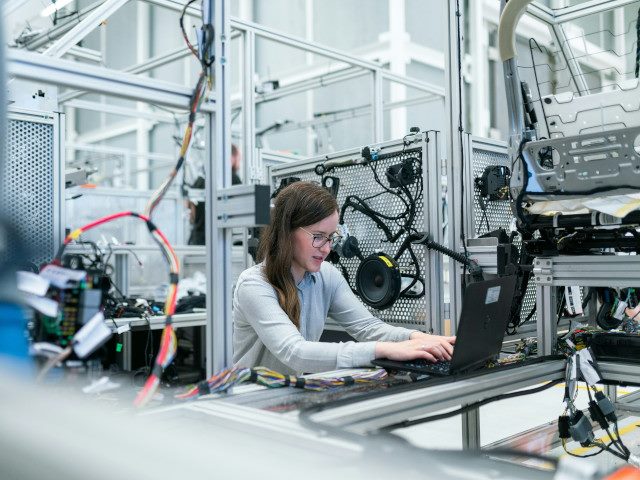 An employee works on a laptop computer in a factory.