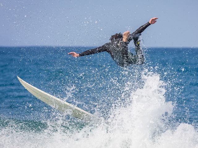  Surfer riding a point break wave wipes out with the board to his left and him suspended in mid-air in Jeffreys Bay, South Africa.