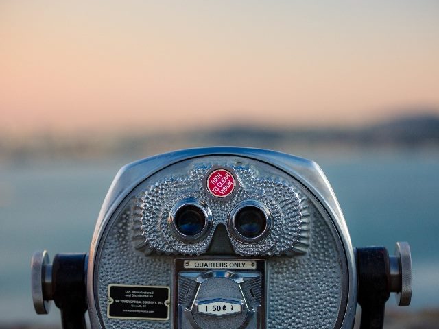 Euro coin-operated binoculars with body of water in background.