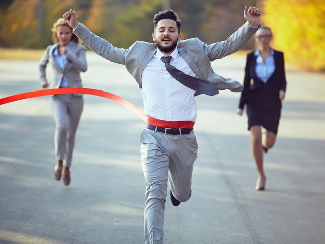 A businessman in a suit, running across the finish line