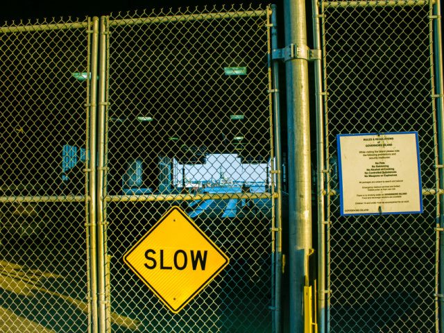closed gate door photo with a slow sign attached