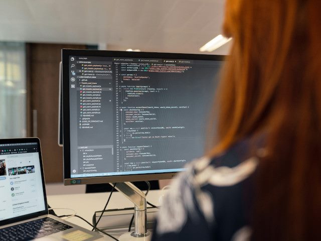 A software engineer writes code on a computer in an office.