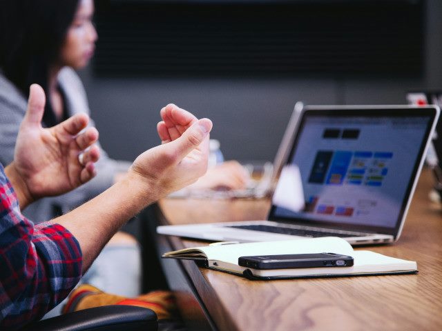 Employees work on laptop computers at a table.