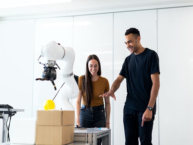 Man and woman smiling at robot engineering