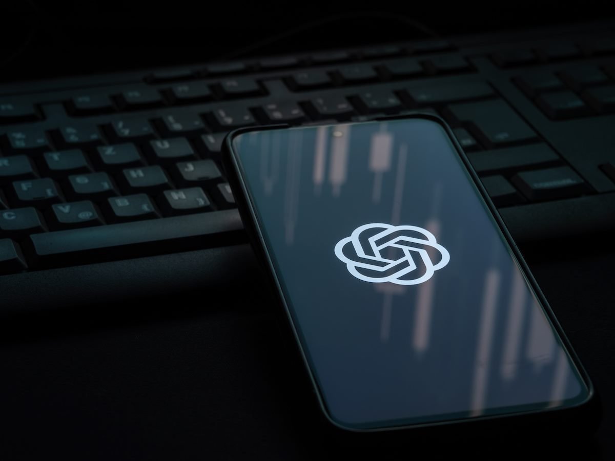 OpenAI logo on smartphone screen laying on computer keyboard