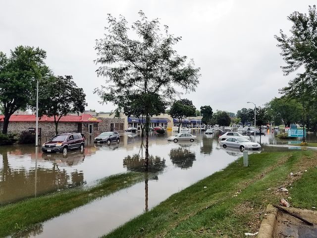 flooded street scene with cars and buildings submerged in water 