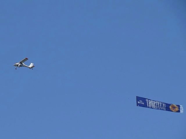 prop airplane with an advertising banner flying behind it