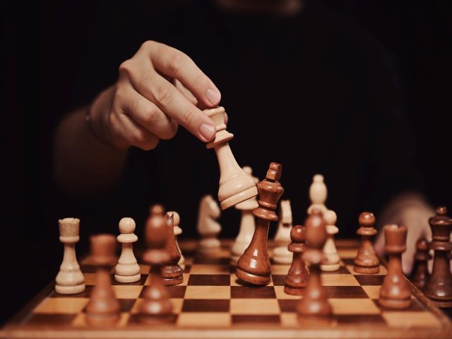 A hand moving chess piece and checkmate during competition.