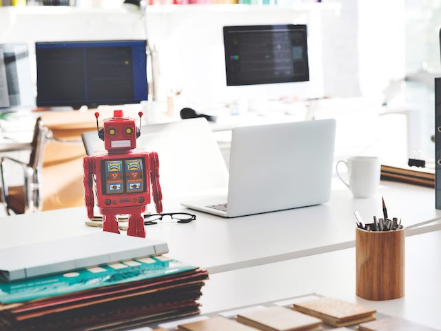 red robot next to a laptop on a desk