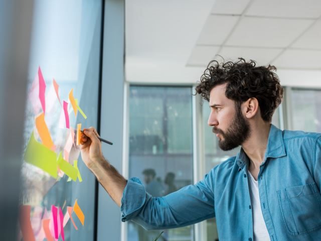 A marketing manager writing on a whiteboard while working on a campaign - data-driven campaign management concept