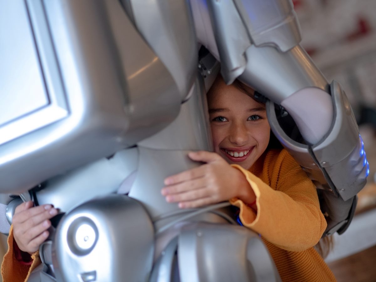 Child hugging a humanoid robot, smiling while interacting closely with the machine, illustrating human trust and emotional connection with AI.
