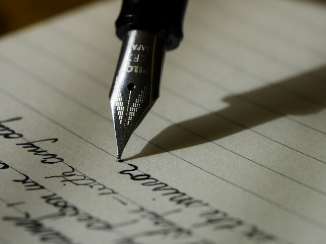 A fountain pen writes words on a paper.
