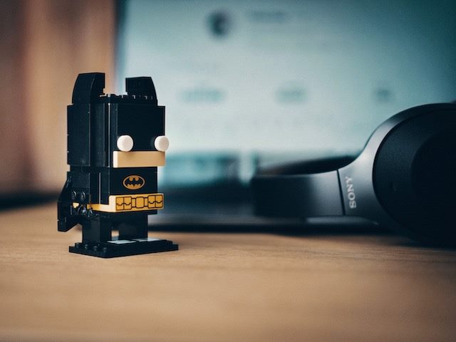 batman figurine near an open laptop with headphones nearby