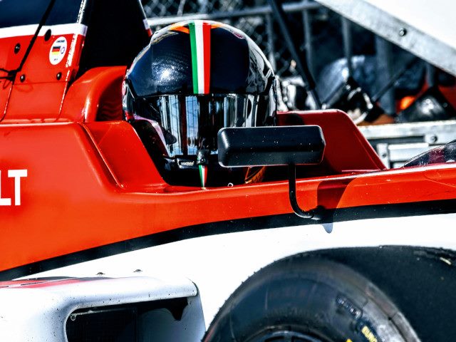 A Formula 1 driver in a race car looking at the camera.