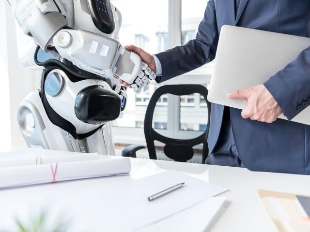 Future businessman with laptop is shaking hands with android
