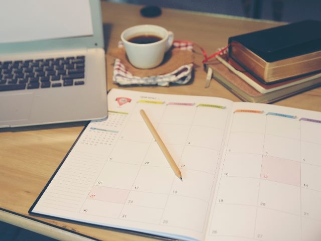 Agenda, planner book, laptop, 2024 calendar, pencil, and cup of coffee placed on business office desk, symbolizing the need to keep AI in analytics tools and processes up to date.