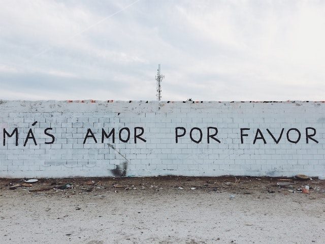 wall with "mas amor por favor" painted on it