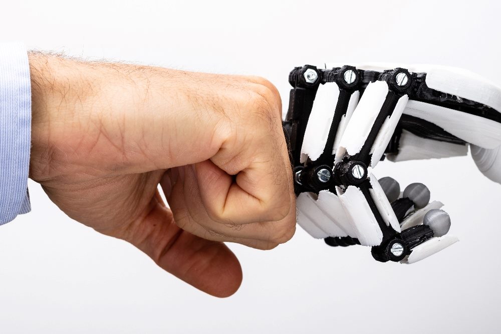 A human hand and a robot hand "fist bump" suggesting the need for AI in customers service and people to work together for improved results