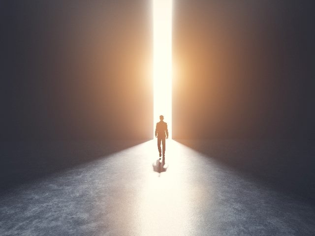 A man walks toward an opening in a door filled with light indicating the future in a piece about AI in marketing at Opticon 2023