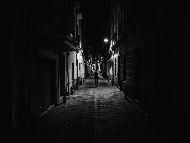 Woman walking alone in the street late at night, in a narrow dark alley. 