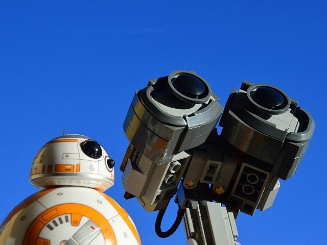 Robot toy friends Sphero BB8 from Star Wars franchise and head of Wall-E from Disney Pixar movie, looking forward up on direct autumn sunshine, with blue skies in background.
