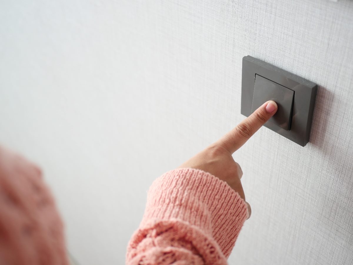 A woman's hand touching a light switch.