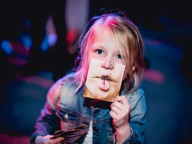 child holding a photograph of someone else's lips in front of their mouth