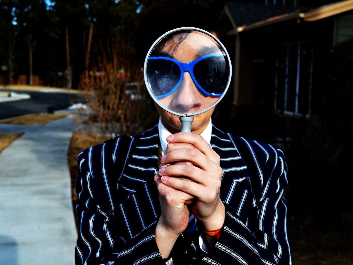 person holding a magnifying glass close to their face, enlarging the size of their glasses