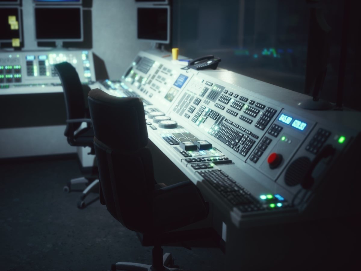 A dark control room with illuminated screens and buttons
