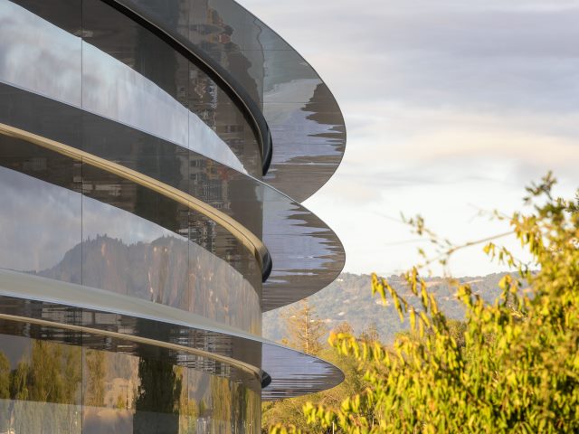 A view of windows at the Apple Park building and foothills in the background.