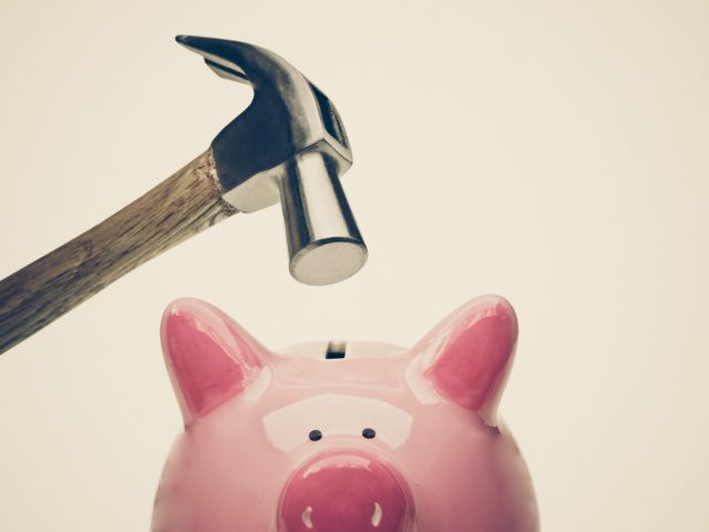 a sad pink piggy bank about to be hit by a hammer